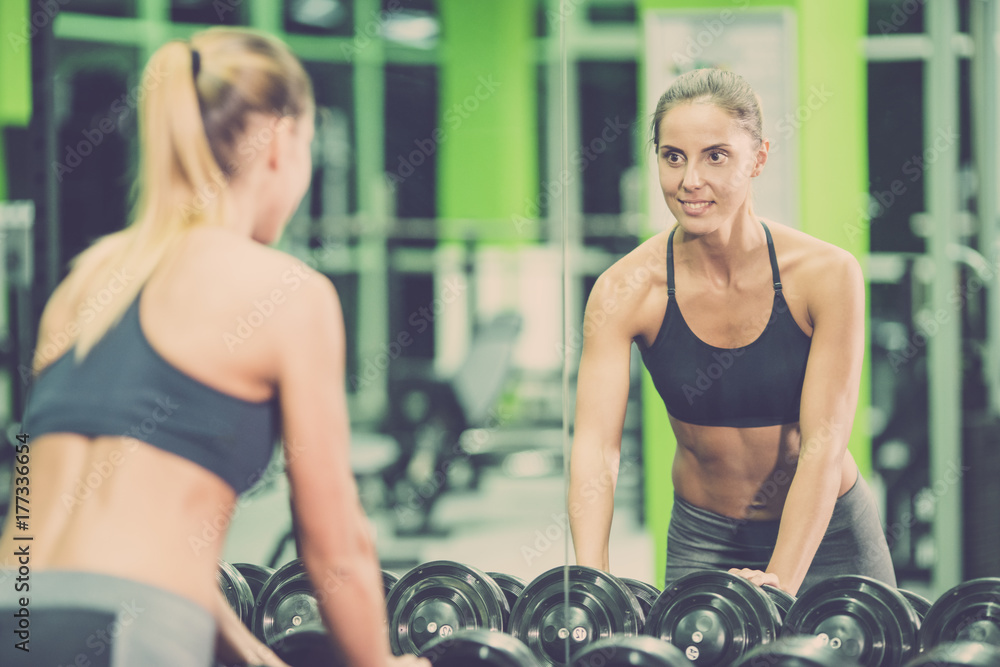 The sportswoman look in the mirror in the gym The sportswoman look in the mirror in the gym