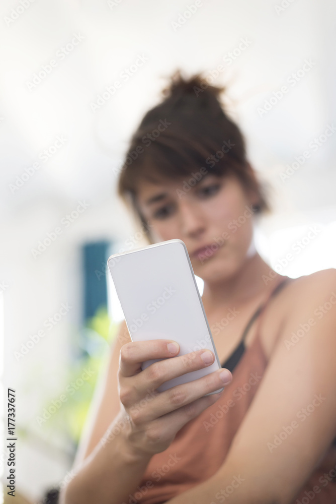 Portrait of happy young businesswoman using mobile phone in office ( Focus on phone )