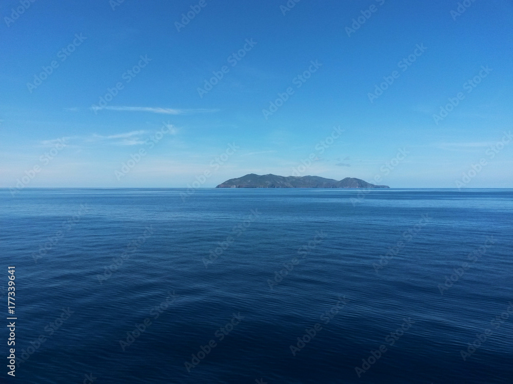 Island on the horizon under the blue sky