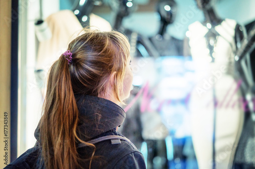 girl looking in the showcase on the night city street