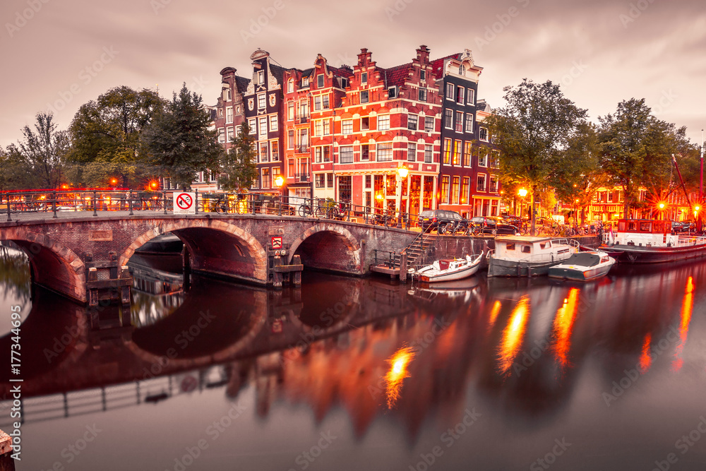 Amsterdam canal, bridge and typical houses, boats and bicycles during evening twilight blue hour, Holland, Netherlands. Used toning