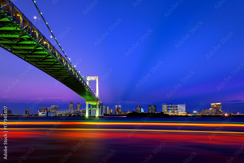 Fototapeta premium Boat traffic at dusk under Rainbow Bridge in Tokyo, Japan
