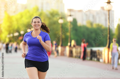 Overweight young woman jogging in the street. Weight loss concept photo