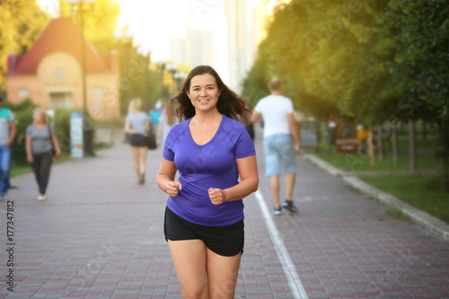 Overweight young woman jogging in the street. Weight loss concept