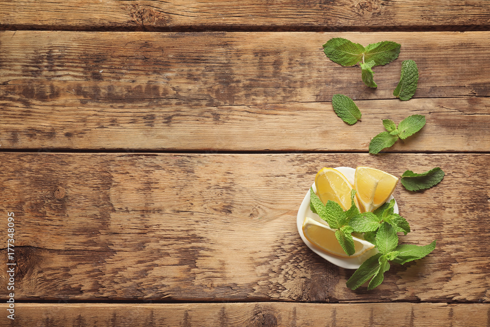 Plate with mint and lemon on wooden background Plate with mint and lemon on wooden background