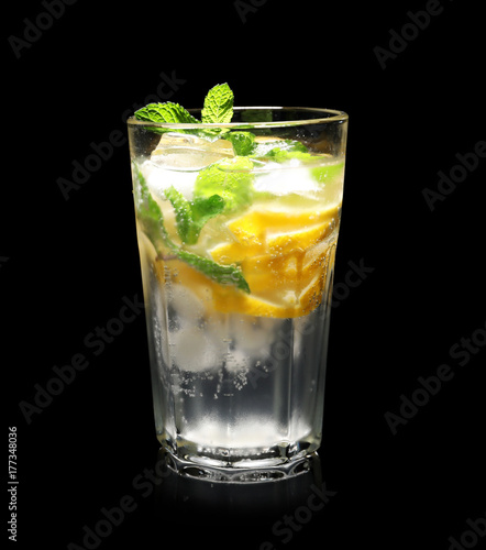 Glass of cocktail with mint and lemon on black background