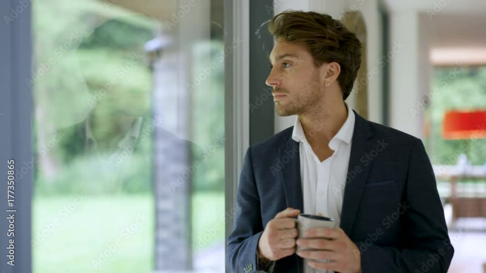 Portrait smiling man in modern home, drinking coffee next to window Portrait smiling man in modern home, drinking coffee next to window