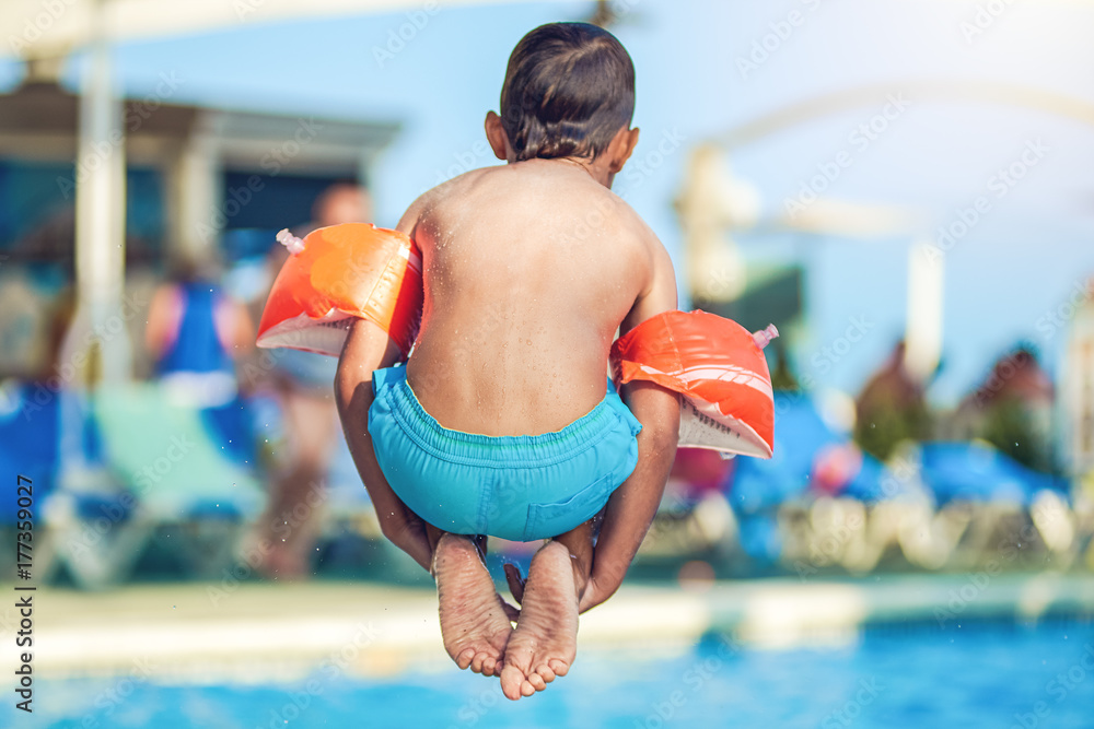 Caucasian boy jumping into the pool.