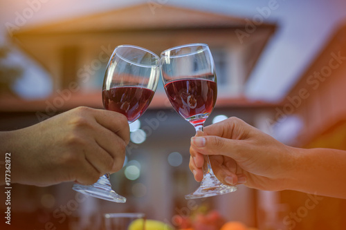 Man hand and woman hand holding a glass of red wine to celebrate Christmas and New Year. The back of the house is a bokeh of light. In the evening when entering the winter.