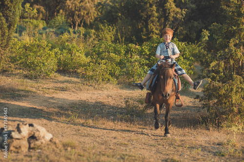 Handsome Young boy with red hair and blue eyes playing with his friend horse pony in forest.Huge love between kid shild and animal pet farm