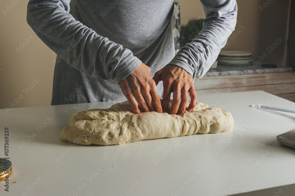 woman massing bread folding the dough into thirds, and sealing with the fingers. Stock Photo