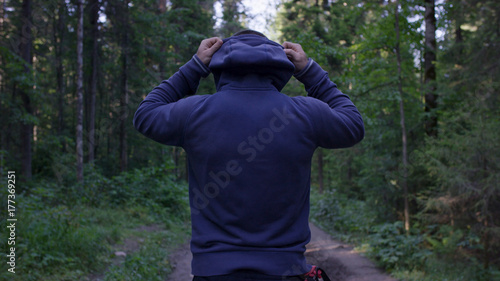 Person in a hood standing. Man in the hood in the woods. Sport in the forest on the nature