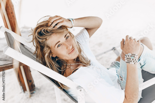 styllish young beautiful woman in casual wear relaxing in chair on the tropical beach photo