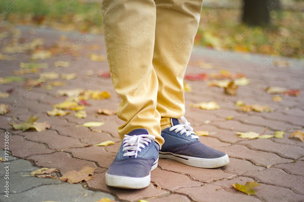 Traveler man in bright trousers and sneakers is on the tile road, walking,sunlight, autumn, Hiking. Traveler man in bright trousers and sneakers is on the tile road, walking,sunlight, autumn, Hiking.