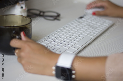 hands of business women with a smart clock with a coffee working on a white keyboard