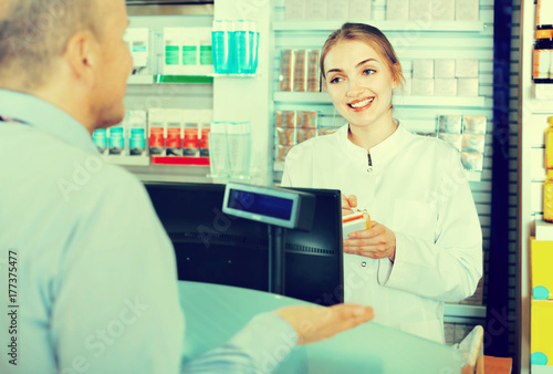 Smiling female pharmacist counseling customer about drugs usage