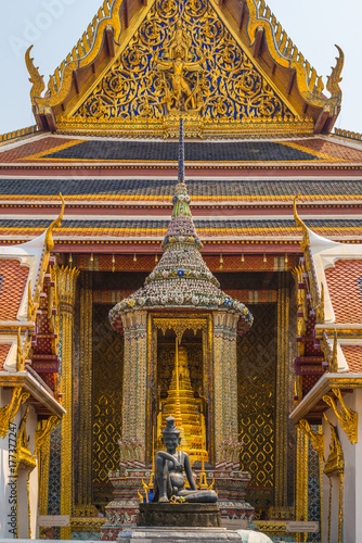 The famous Buddhist temple Wat Phra Kaew, located in the The Grand Palace in the historic centre Bangkok. In the foreground, the statue of the Seated Hermit, behind, the statue Phra Phothi That Phima photo