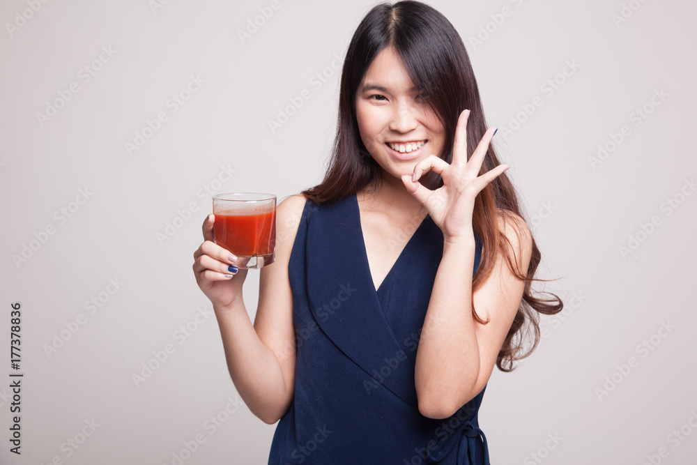 Young Asian woman show OK with tomato juice.