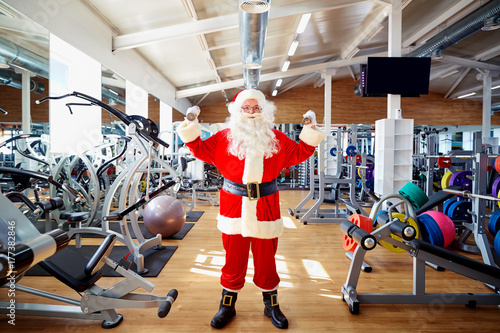 Fototapeta Naklejka Na Ścianę i Meble -  Santa Claus in the gym doing the exercises.