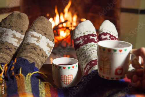 A man and a woman in front of a fireplace in warm socks. New Year. Christmas.