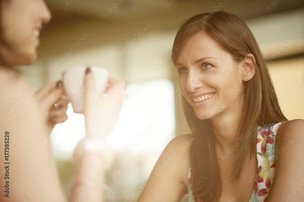 Two girls chatting and drinking coffee while sitting in cafe Two girls chatting and drinking coffee while sitting in cafe