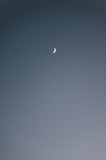 A crescent moon in the blue sky.
