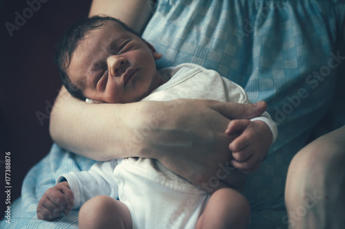 One day old baby boy sleeping on his mother's lap photo