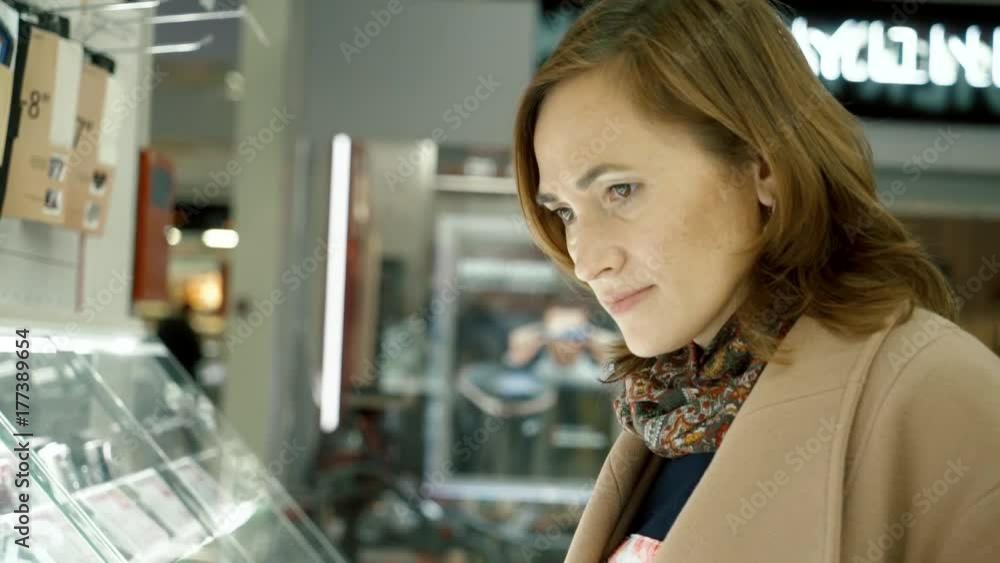 A woman in a home appliance shop looks at the shop window with cameras. A woman in a home appliance shop looks at the shop window with cameras.