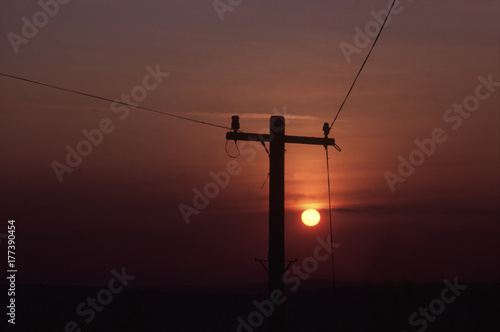 Silhouette of single telegraph pole at sunset
