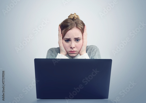 Young girl in front of a laptop clutched her head. 