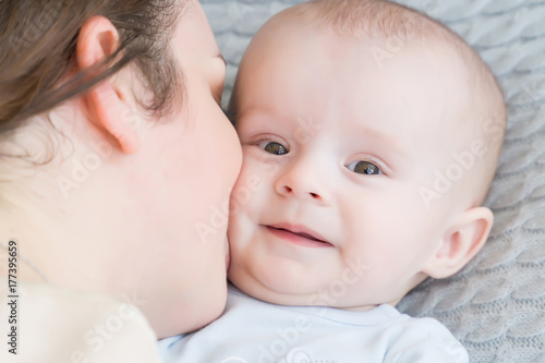 Close-up portrait of happy young mother hugging and kissing his sweet adorable child. Indoors shot, concept image