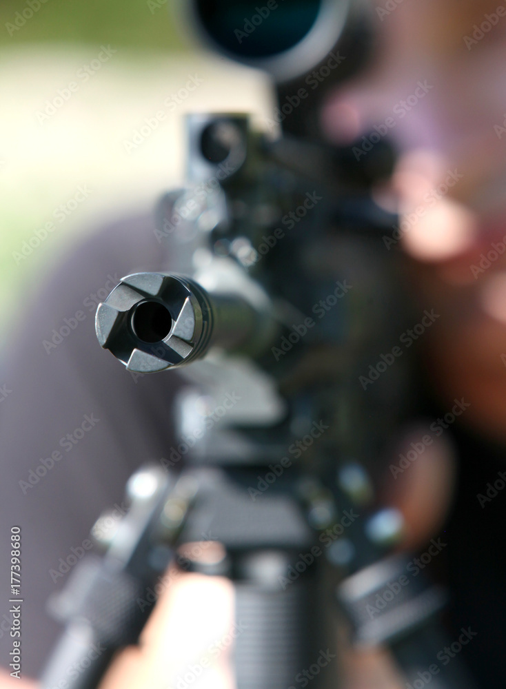 Black MilitaryStyle Rifle Aimed Forward With Blurred Background And