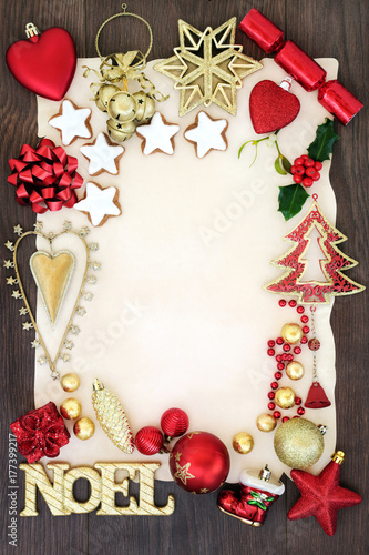 Noel sign and christmas decorations forming an abstract background border on parchment paper on oak wood.