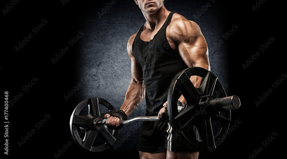 Fototapeta Młody seksowny bodybuilder z perfect ciałem robi ćwiczeniu z barbell na czarnym tle.