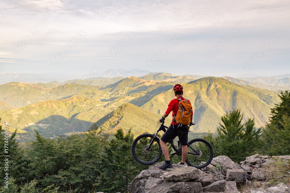 Mountain biker looking at view on bike trail in autumn mountains.
