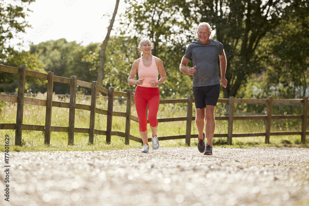 Obraz premium Healthy Senior Couple Enjoying Run Through Countryside Together