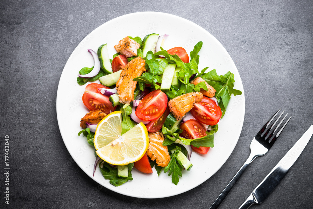 Fresh salad with salmon and vegetables on black background. Fresh salad with salmon and vegetables on black background.