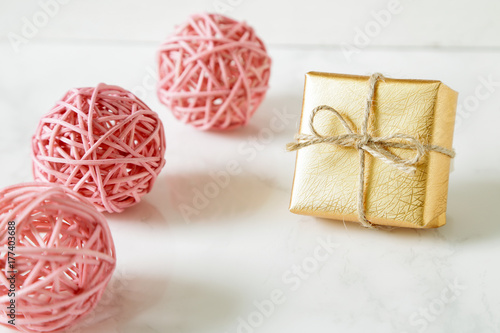 Gold gift box and pink ornaments on table