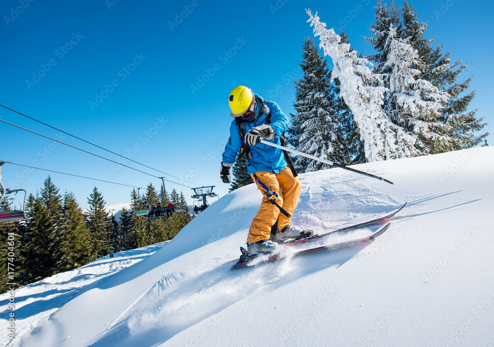 Shot of a professional freeride skier riding down in the Carpathians mountains at winter resort on a sunny day. Blue sky and winter forest on the background Shot of a professional freeride skier riding down in the Carpathians mountains at winter resort on a sunny day. Blue sky and winter forest on the background