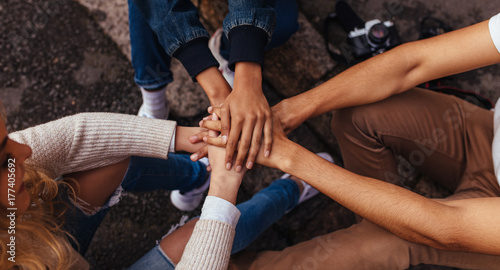 Group of friends sitting together stacking their hands on one an © Jacob Lund