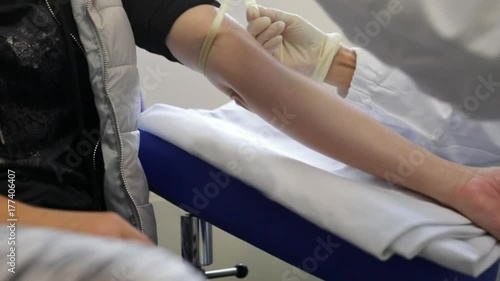 Slow motion of nurse putting a tourniquet on the arm of a patient woman waiting for blood collection in blood testing laboratory. Concept of anxious patient and fear for blood. photo