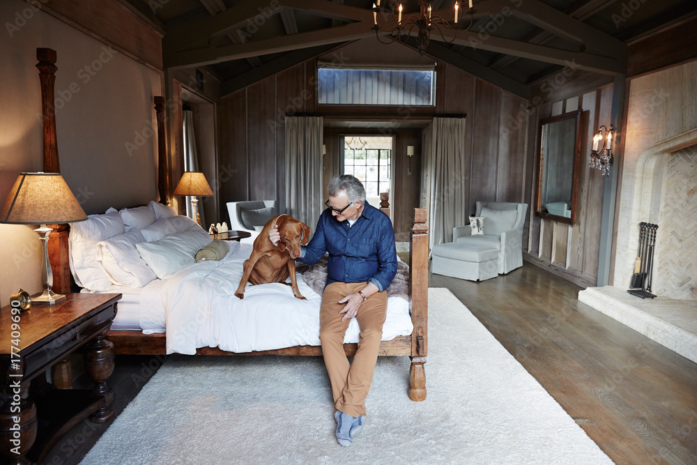 Mature man with grey hair relaxing with his dog in bedroom Mature man with grey hair relaxing with his dog in bedroom