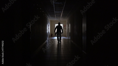 Silhouette of a man runs through the dark corridor.