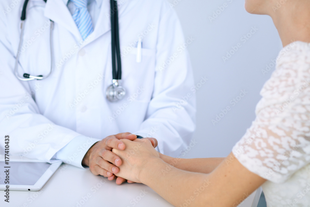Doctor reassuring his female patient by touching her hands while talking. Symbol of support and trust in medicine Doctor reassuring his female patient by touching her hands while talking. Symbol of support and trust in medicine
