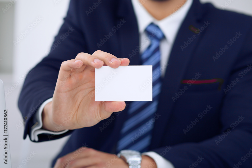 Unknown businessman or lawyer giving a business card while sitting at the table, close-up. He offering partnership and success deal Unknown businessman or lawyer giving a business card while sitting at the table, close-up. He offering partnership and success deal