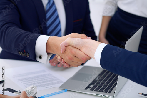 Business handshake at meeting or negotiation in the office, close-up. Partners are satisfied because signing contract or financial papers