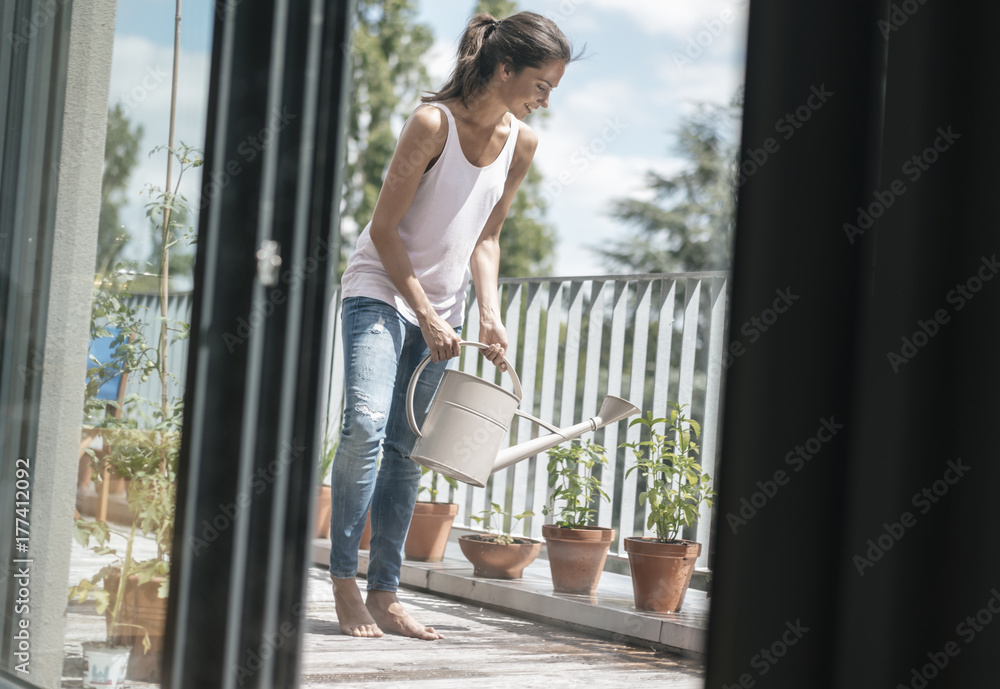 Smiling woman on balcony watering plants