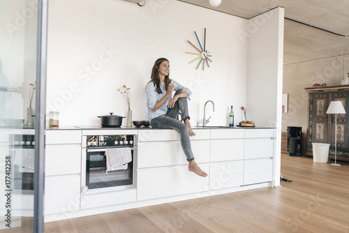 Smiling woman relaxing in kitchen at home photo