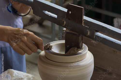 The technician form wet clay to a bowl with tool