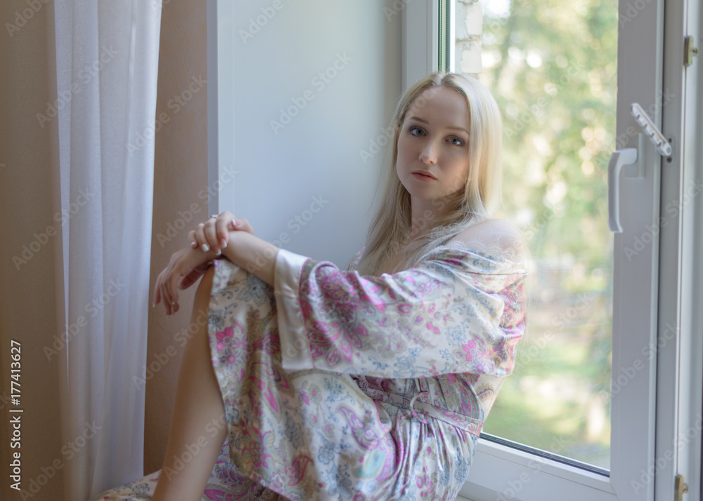 Beautiful young woman sitting by the window. Selective focus.